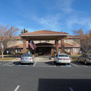 A view of a building entrance with American flags and parked cars in front.