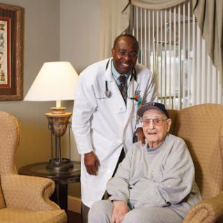 A healthcare professional posing with an elderly patient in a cozy indoor setting.