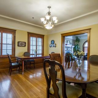 A spacious dining room with wooden floors, elegant furniture, and a chandelier.