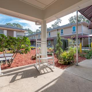 A peaceful courtyard with a rocking chair surrounded by well-maintained gardens and multi-story buildings.