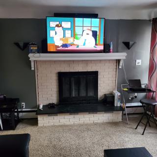 A cozy living room with a television mounted above the fireplace, showcasing a cartoon.