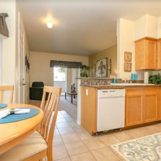 A cozy kitchen featuring wooden cabinets and a dining area with a table set for mealtime.