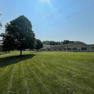 A sunny day with a large building and a tree on a well-maintained lawn.