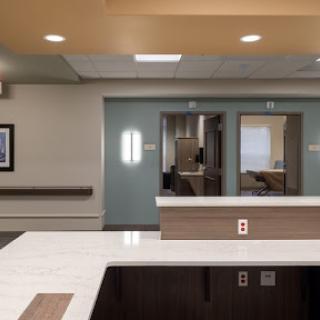 A modern hospital reception area with a sleek design, featuring a reception desk and access to patient rooms.