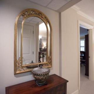 A hallway with a decorative mirror above a wooden table, featuring an ornate vase.