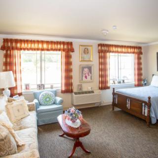 A cozy bedroom with vintage-style furniture and ample natural light streaming through the windows.