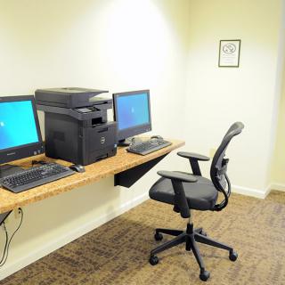 A small office workspace with dual monitors and a printer.