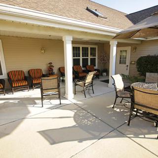 A sunny outdoor patio with chairs and tables, featuring an umbrella for shade.