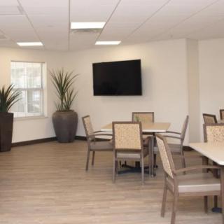A modern meeting room with tables, chairs, and a television.