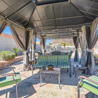 A cozy outdoor patio area with a gazebo providing shade over comfortable seating and a table.