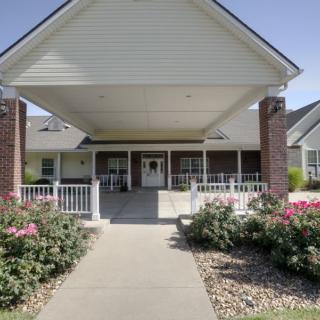 A welcoming entrance to a residential building with a covered porch and landscaped pathway.