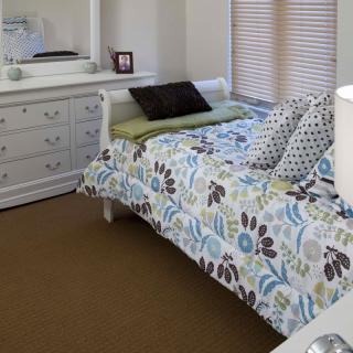 A cozy bedroom with a floral-patterned bedspread and a matching dresser with a mirror.