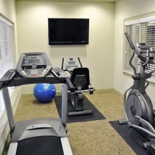 A small indoor gym with exercise equipment including a treadmill, elliptical machine, and stationary bike.