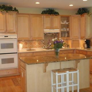 A modern kitchen with wooden cabinets, a central island, and built-in appliances.