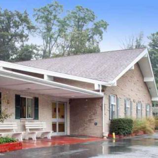 A single-story building with a covered entrance and surrounding foliage.