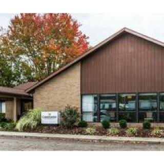 A small office building with autumn trees in the background.