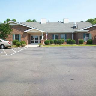 A brick building with a front entrance and adjacent parking lot.