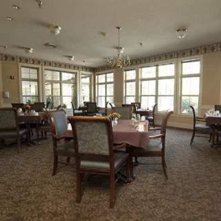 A spacious dining room with large windows and multiple tables and chairs.