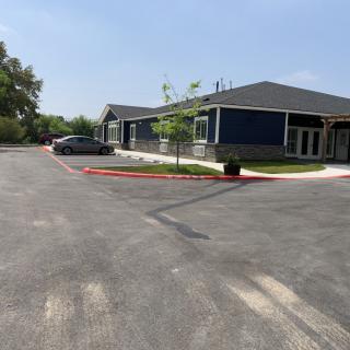 A building with a parking lot and a car parked outside on a sunny day.