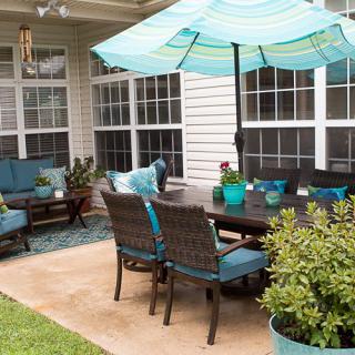 A cozy backyard patio with comfortable seating and a large umbrella.