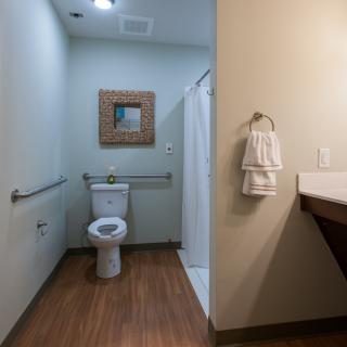A clean and modern bathroom with a toilet, mirror, shower, and towels.