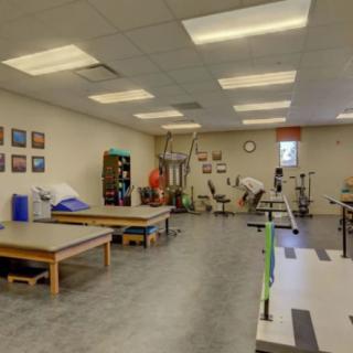 A physical therapy clinic with therapy tables and exercise equipment.