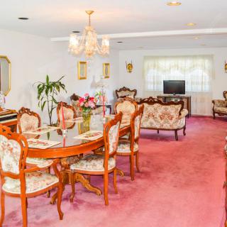 A vintage-style dining room with floral upholstered furniture and a pink carpet.