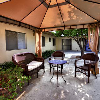 A cozy outdoor patio set under a gazebo with wicker chairs and a small table.