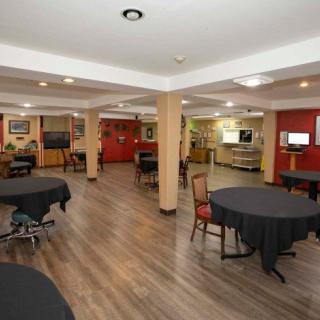 A spacious indoor dining area with wooden flooring, featuring tables and chairs arranged neatly under soft lighting.