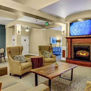 A cozy living room interior with a fireplace, seating area, and television.