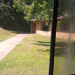 A peaceful view of a building surrounded by greenery and a walkway leading up to it.