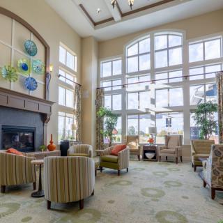A spacious and well-lit lounge area featuring comfortable seating, large windows, and a cozy fireplace.