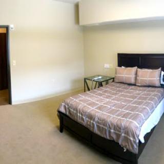A cozy and minimalistic bedroom featuring a neatly made bed and a side table.