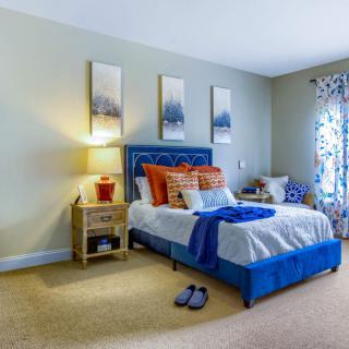 A cozy bedroom with a blue-themed bed, decorative pillows, and wall art complementing the ambiance.