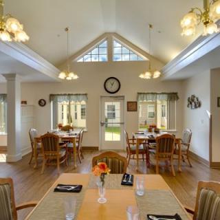 A bright and inviting dining room with multiple tables and chairs, well-lit by hanging ceiling lights.