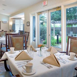 A well-set dining area with neatly arranged tables and chairs by large windows.