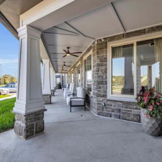 A beautiful covered porch featuring stone pillars and comfortable seating, perfect for enjoying the outdoors.