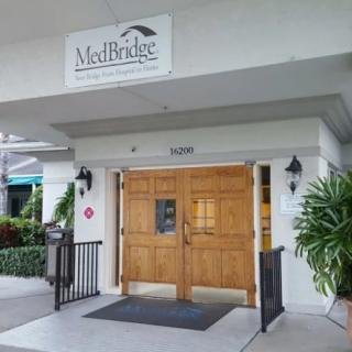 Entrance to a healthcare facility with wooden double doors and a sign above.