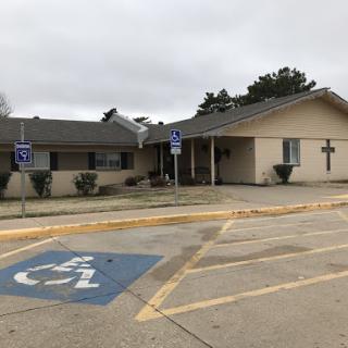 A handicap accessible church with a prominent cross in a cloudy environment.