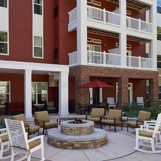 A cozy outdoor patio area with a fire pit and comfortable seating outside an apartment building.