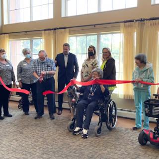 A group of individuals gathers for a ribbon-cutting ceremony, marking the opening of a new facility or service.