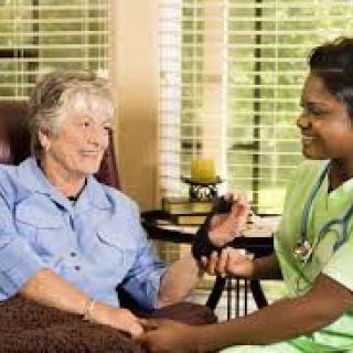 A nurse taking the blood pressure of an elderly patient at home.