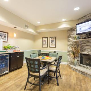 A cozy dining area with a table and chairs, featuring a stone fireplace and a television mounted above.