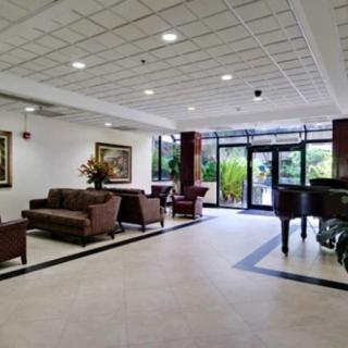 A modern lobby with comfortable seating, a grand piano, and large glass doors leading outside.