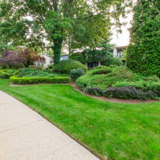 A beautifully landscaped garden with lush green lawns and a winding pathway.