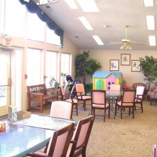 A bright indoor seating area with tables, chairs, and a small playhouse.