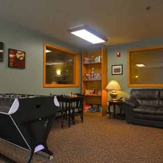 A cozy game room featuring a foosball table, seating area with couches, and shelves with books.