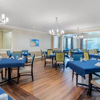 A spacious dining area with elegantly set tables and chairs, illuminated by chandeliers.