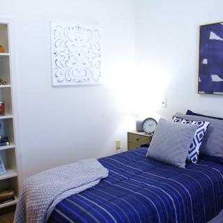 A neatly arranged bedroom with a blue-themed decor and minimalist design.