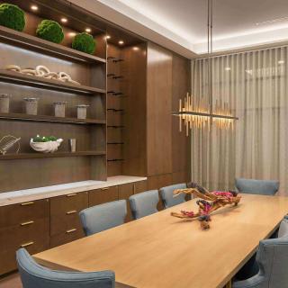 A modern dining room with wooden furniture, featuring a stylish chandelier and decorative elements.
